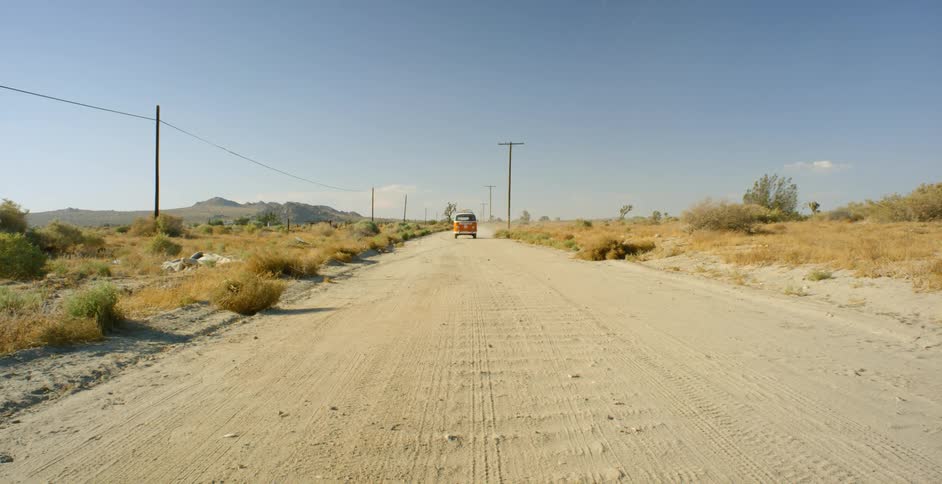 Van drives down a dirt road on a clear day