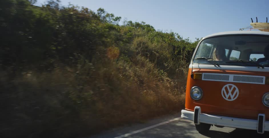 The orange van travels on a sunny day