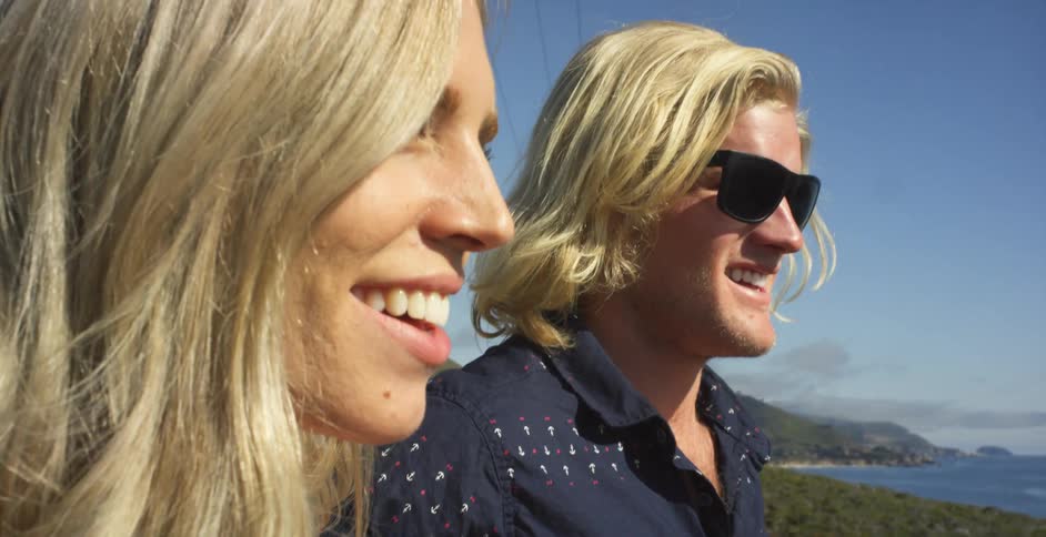 Man and woman smile while standing on a coast