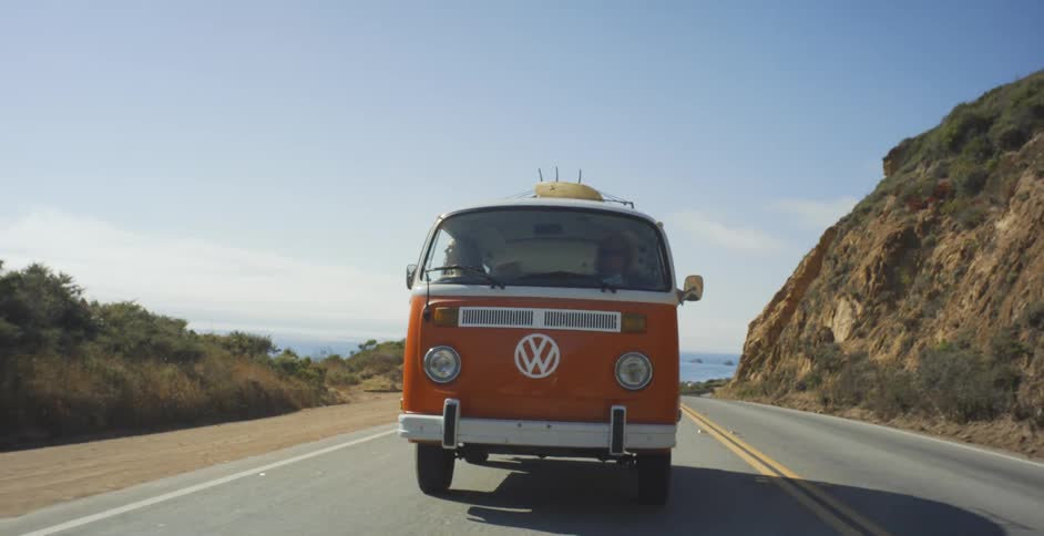 A van is traveling on the road near the coast