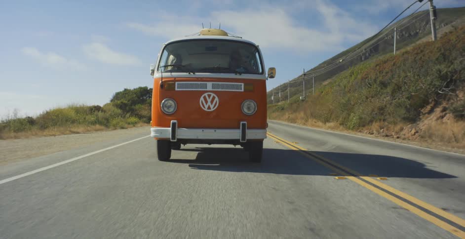 Orange van drives down the highway under a blue sky