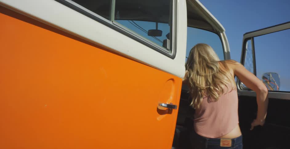 Woman gets into an orange and white van