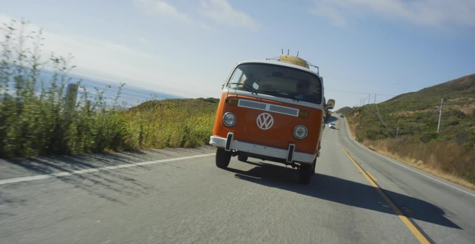 A volkswagen bus is driven on a coastal road