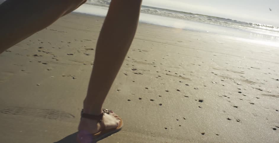 A woman walks on a sandy beach