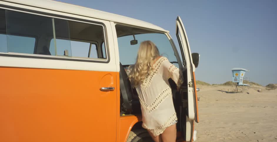 Woman climbs into a volkswagen bus on a beach