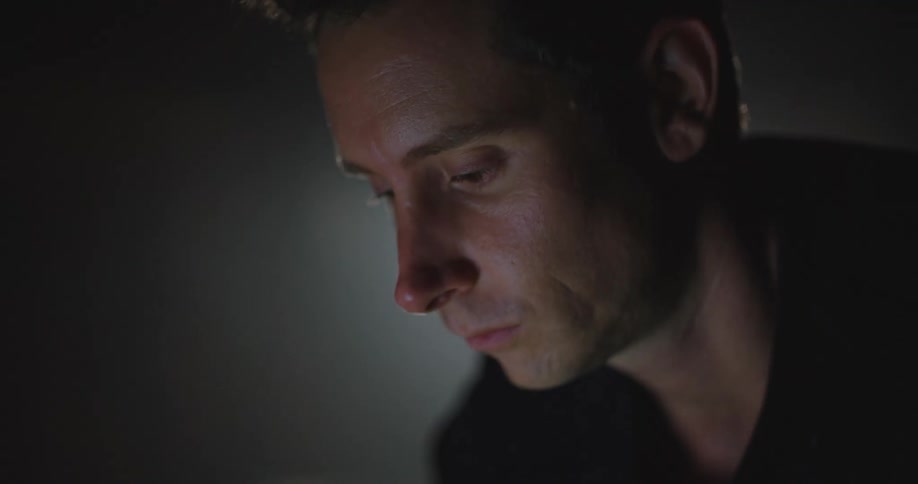 Young man working on a laptop inside a dimly lit room