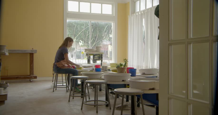Woman on a stool spinning her pottery