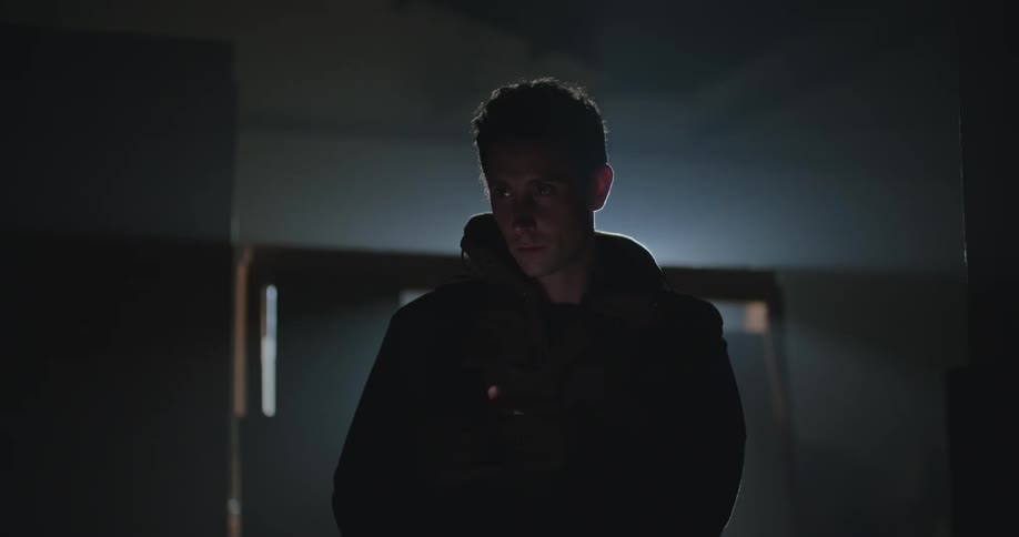 Man wearing coat and viewing mobile phone turns on lights in room