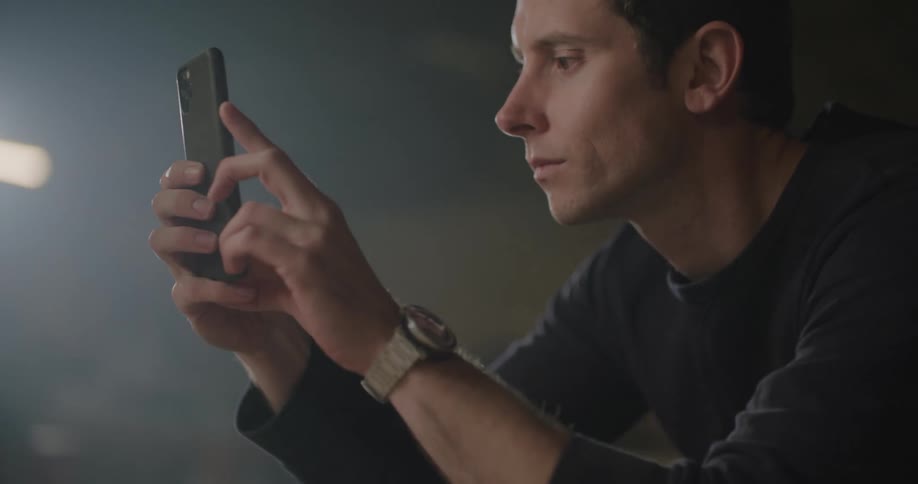 A man leans forward and takes a photo with his phone