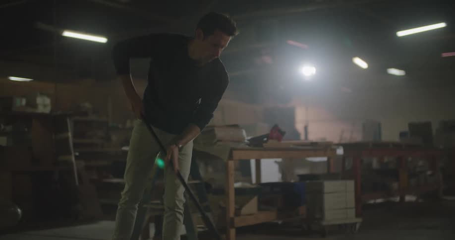 A man sweeps up sawdust in a woodworking shop