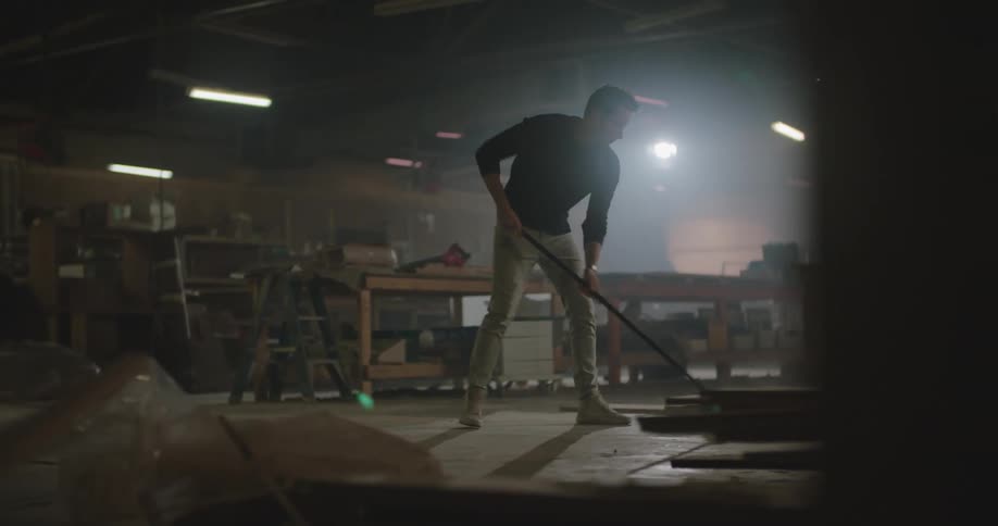 An employee sweeping the floor in a workshop