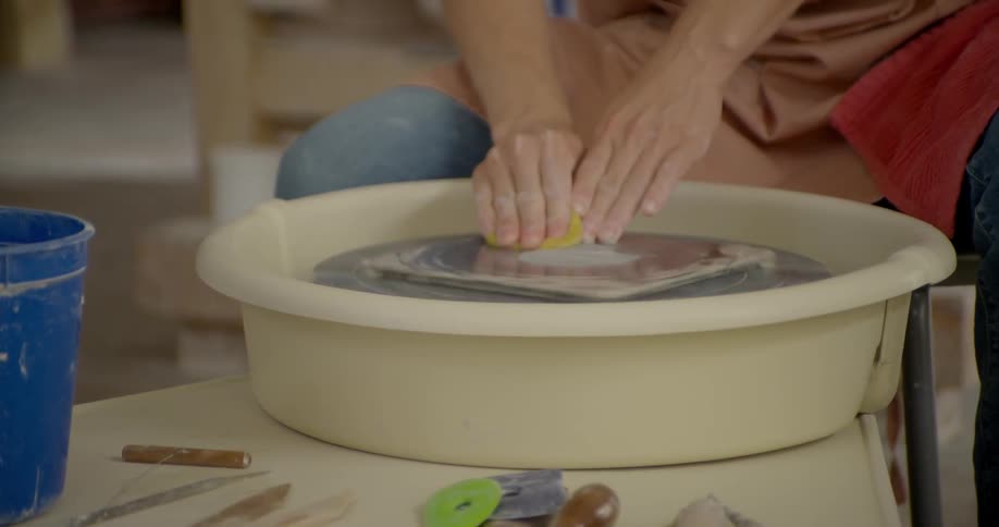 A woman is using a clay wheel