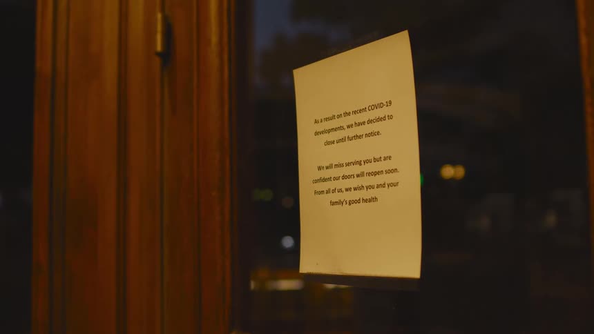 A notice taped to a business door announcing they are closed due to the pandemic
