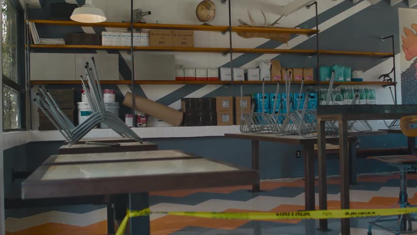 Yellow caution tape tied to the tables of a closed restaurant