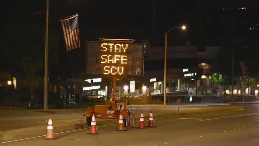 Cars drive by a flashing sign on a twoway road at night