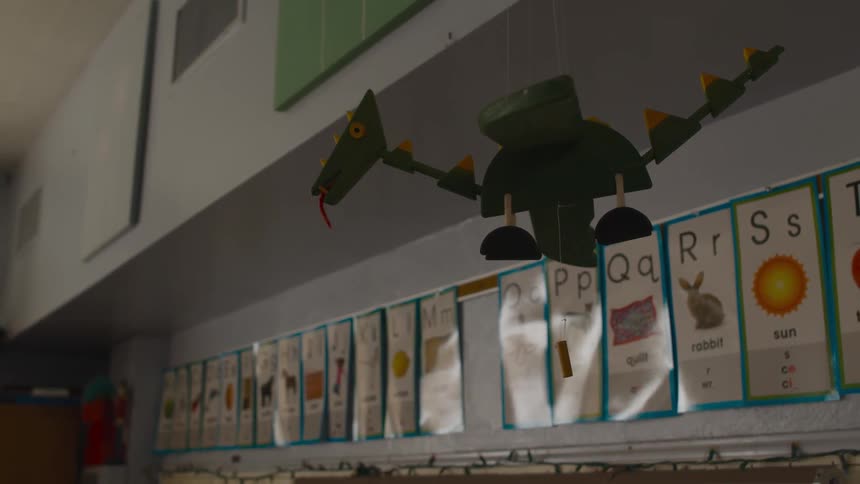 Dragon model hands from ceiling near row of alphabet letters in school room