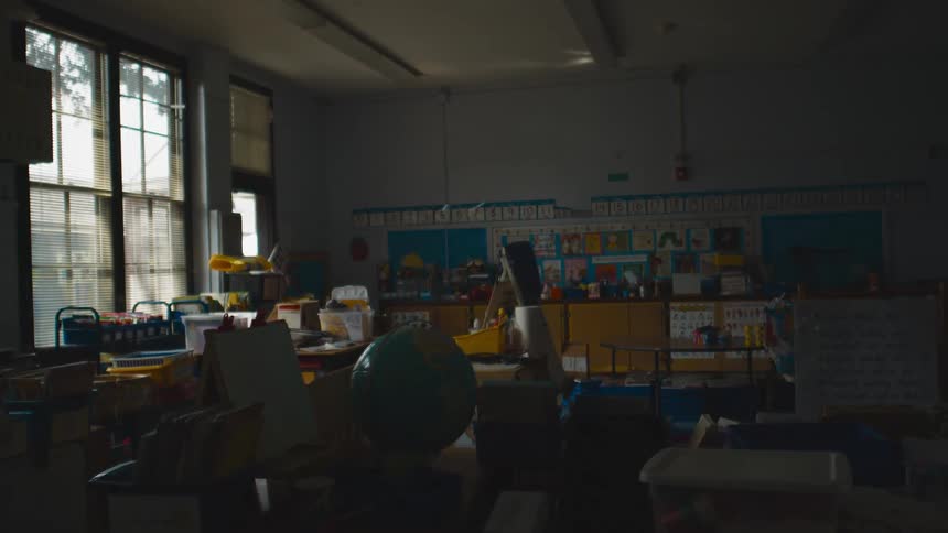 An empty classroom partially lit by sunlight on a cloudy day