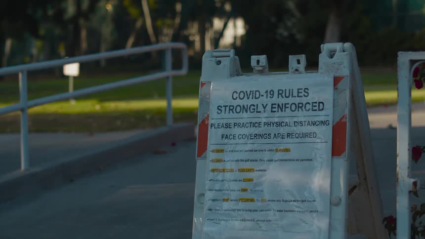 Sign listing covid19 rules sits near a fence