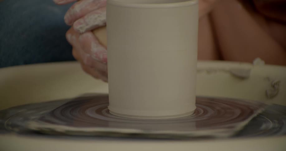 A person is forming clay on a spindle