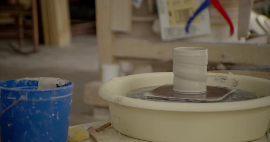 A clay cup spinning on a potter's wheel