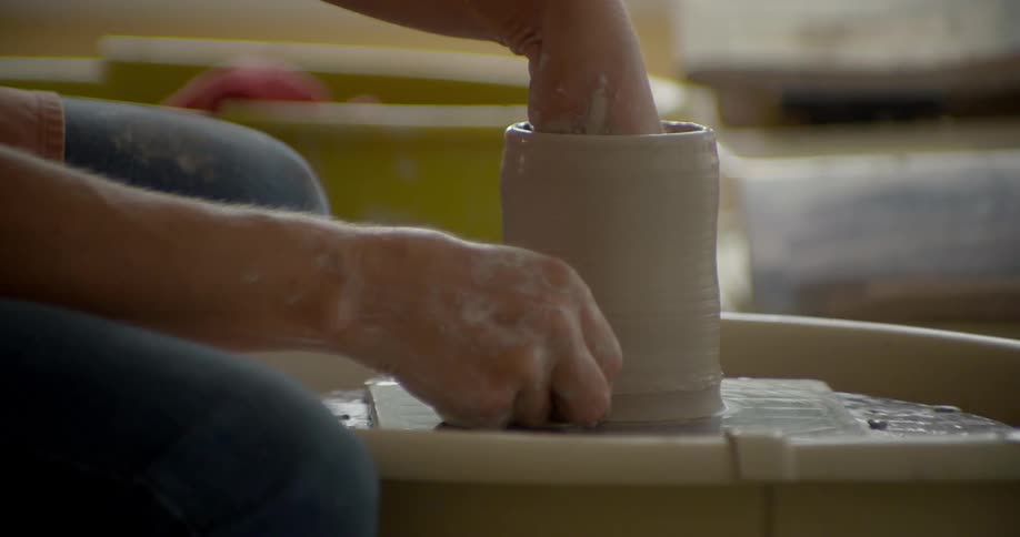 A person is spinning clay on a wheel