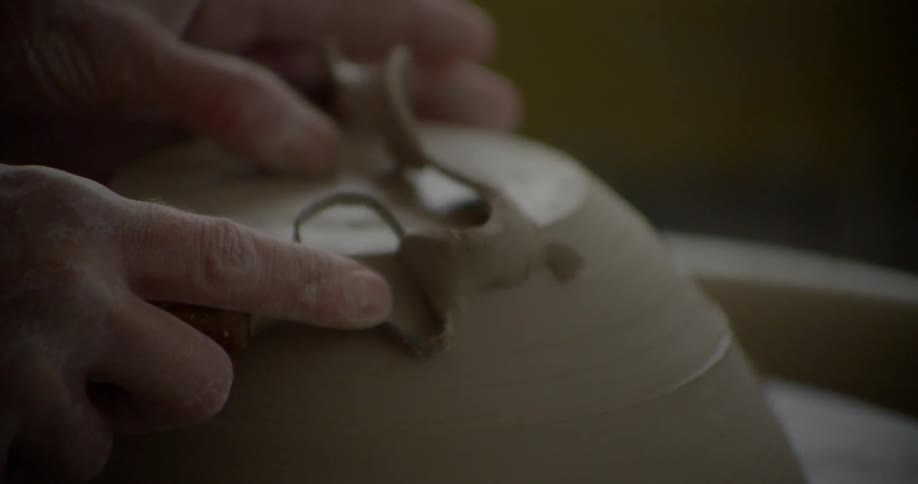 A person is carving clay into a bowl