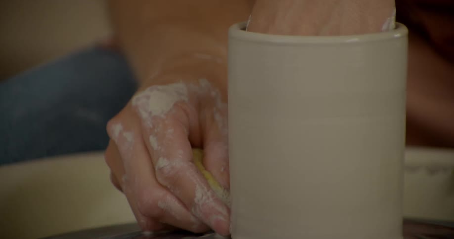 Person molding clay as it's spinning in front of them