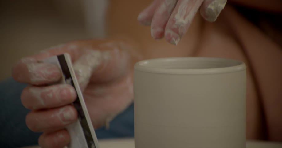 A person is using a card to shape clay