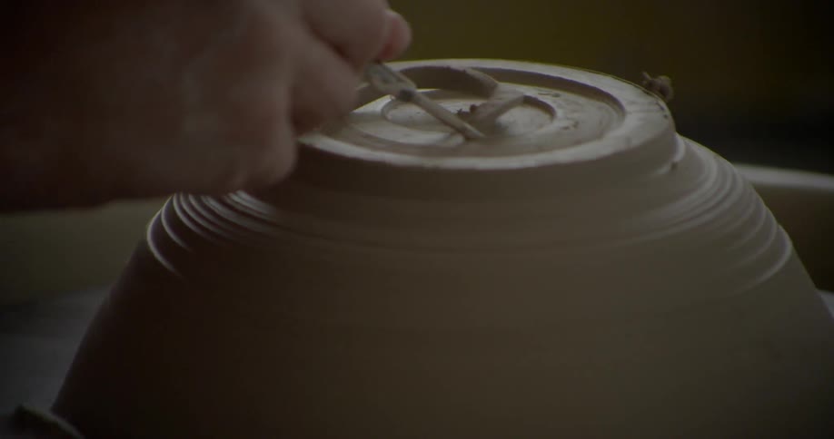 A clay vessel is worked on a pottery wheel