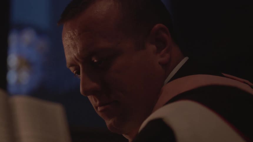 A man slowly looks up in a dark area