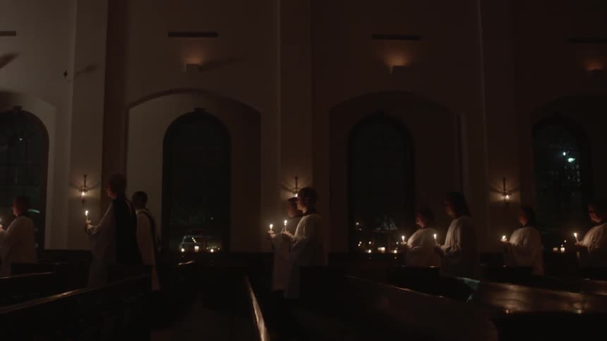 People with lit candles walking down the aisle at church