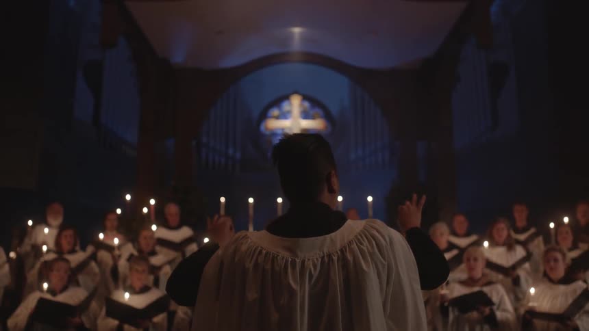 A man conducts a robed choir in an ornate church