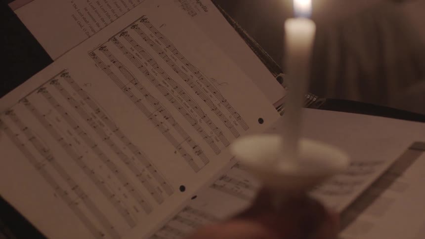 A church choir performs while holding candles