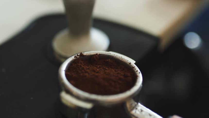 A person in a room with a scoop of coffee grounds next to a table