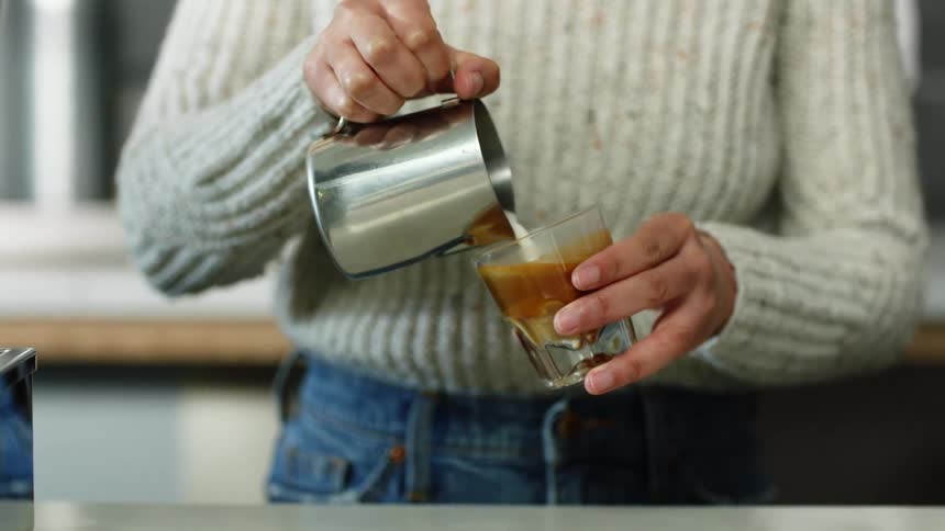 A woman is making a coffee drink indoors