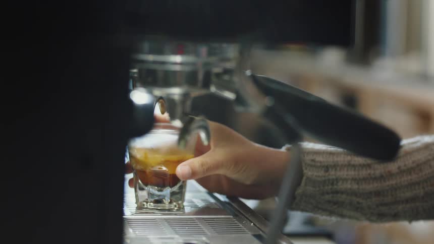 A woman pours a shot of espresso in a cafe