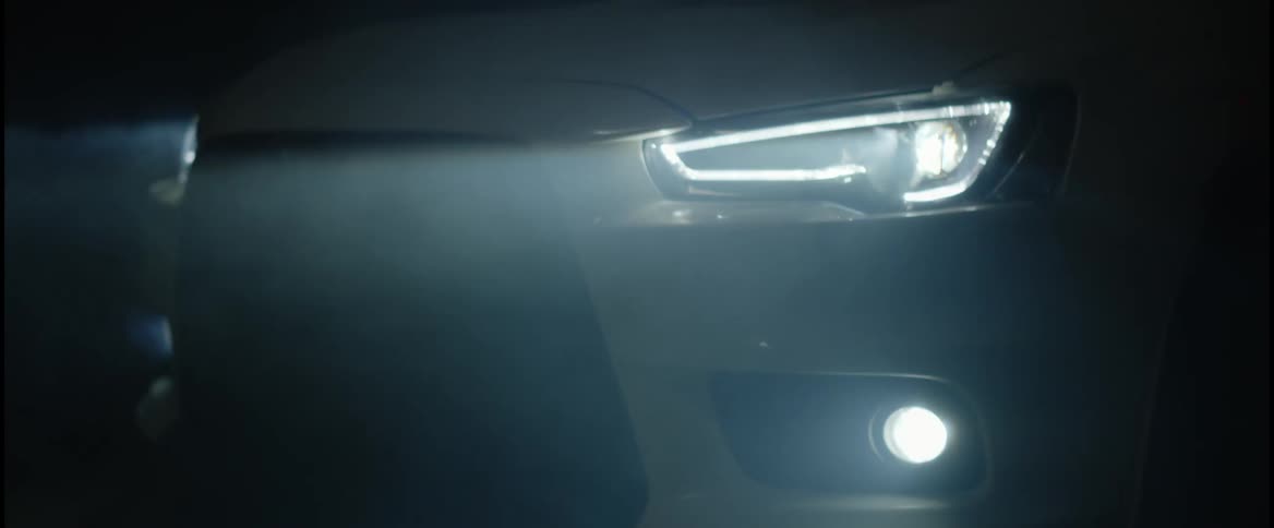 A car is driving on a foggy night
