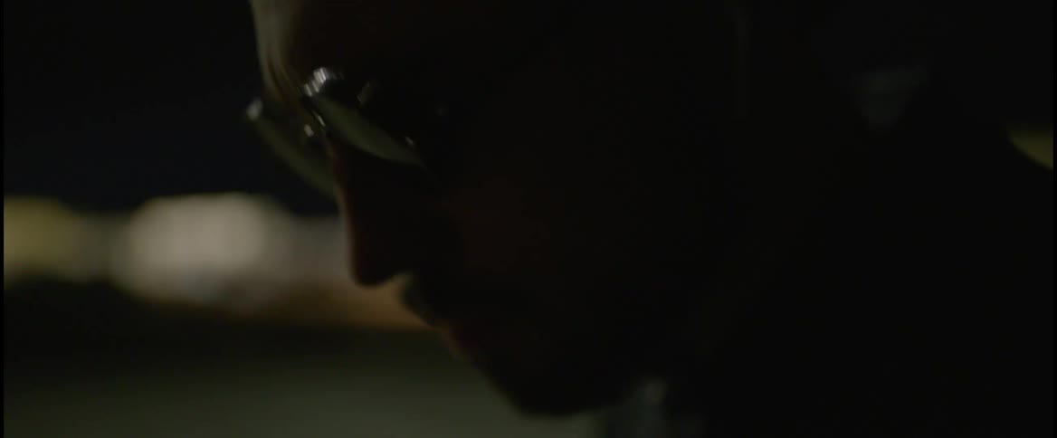 Close up of the face of a man wearing sunglasses bobbing his head to music