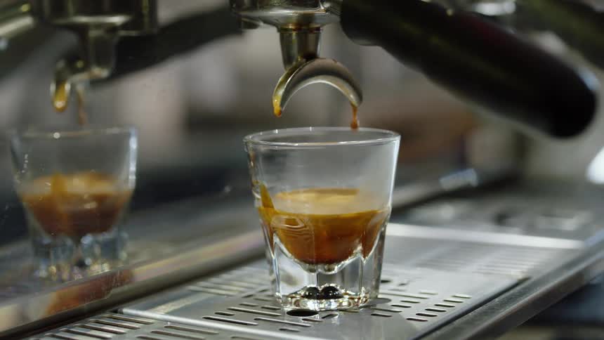 The small glass is being filled by the machine