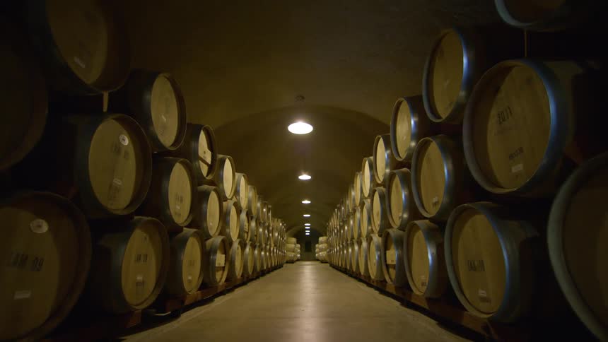 A room with barrels in a tunnel with lights hanging from the ceiling above