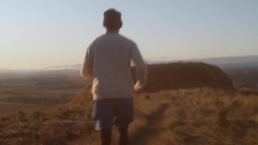 A man runs through a grassland during the day