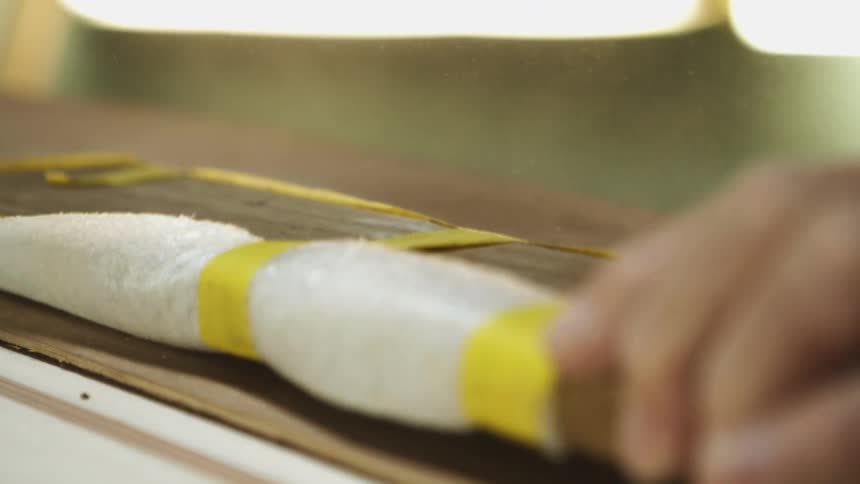 A person is hammering wood outdoors during the day