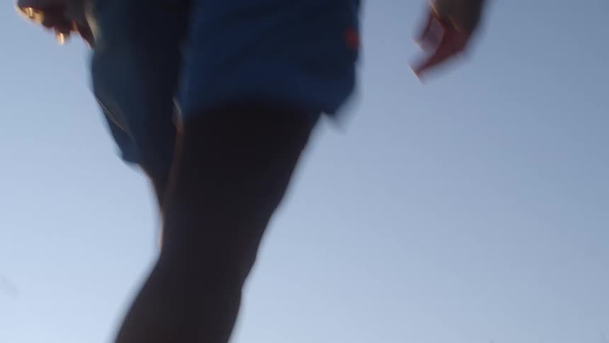 Man jogs running up a hill at sunset