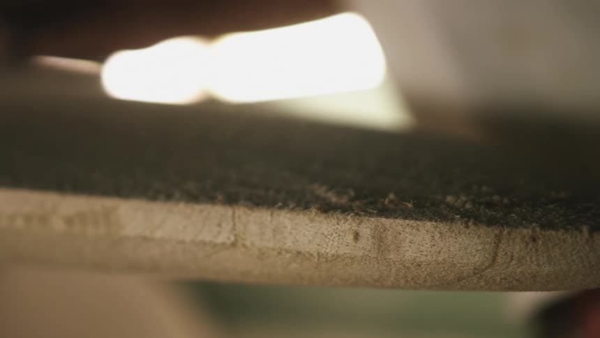 An employee sanding a board in a shop