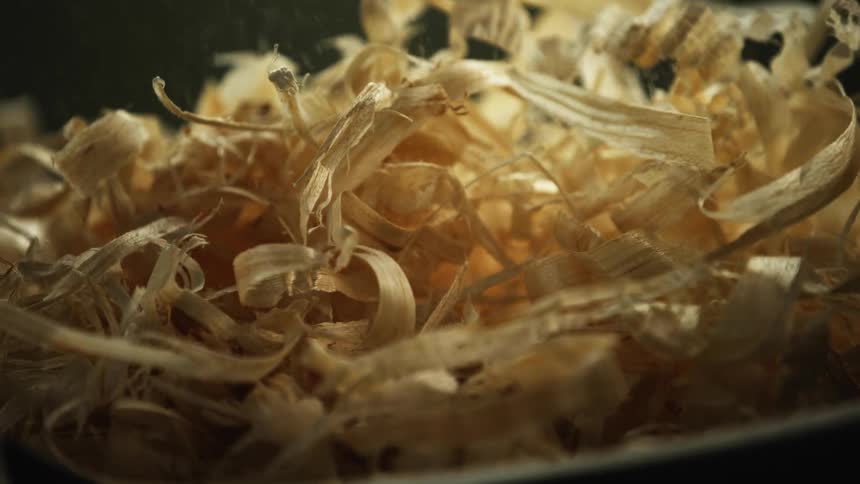 Wood shavings and sawdust fall into a bucket