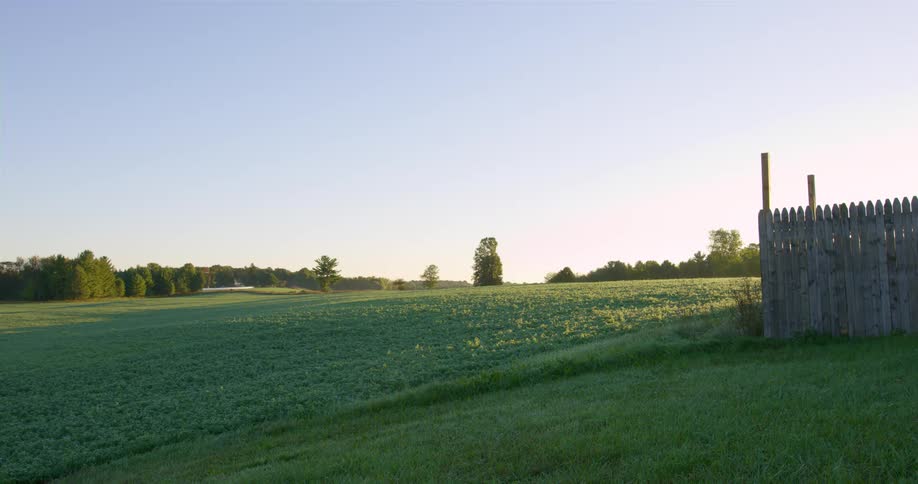 A vast green field sits behind a picket fence