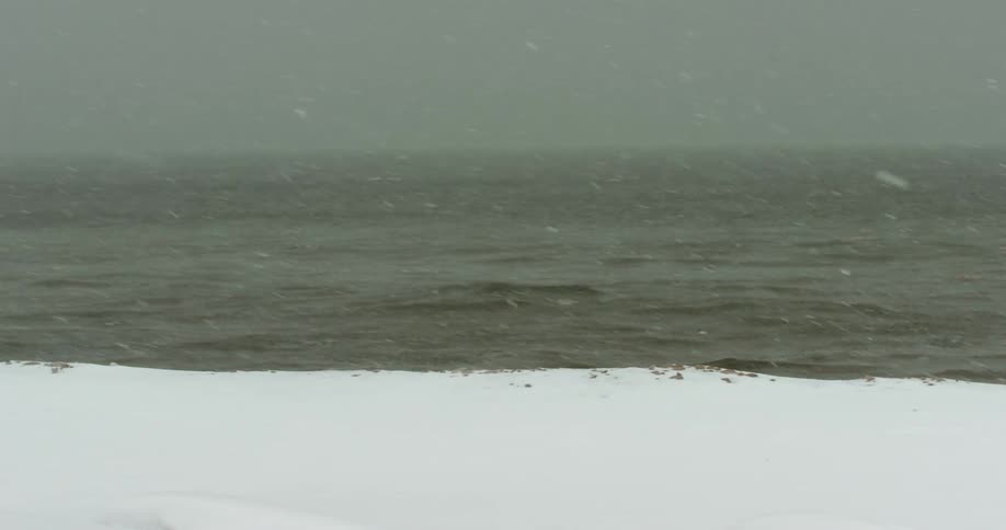 Snow falling near the coast with the ocean sky and clouds in the background