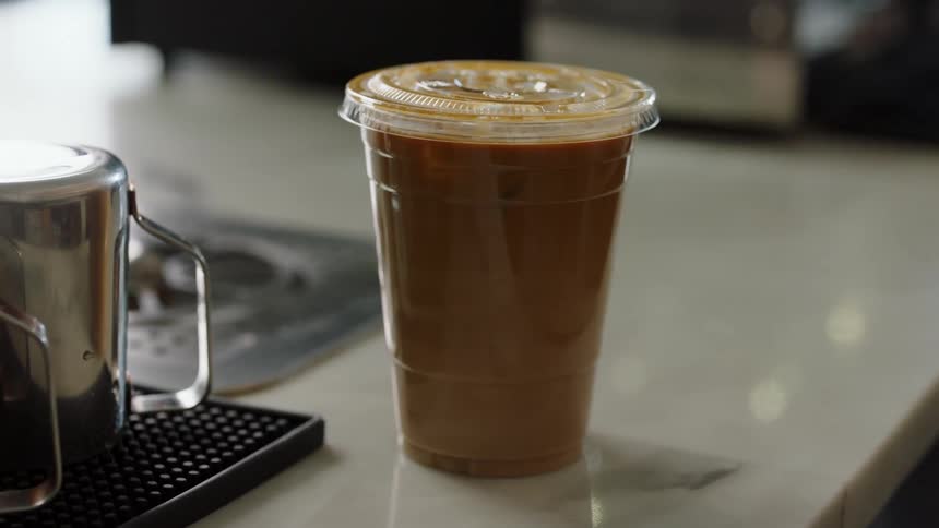 A coffee drink is placed on a table during the day