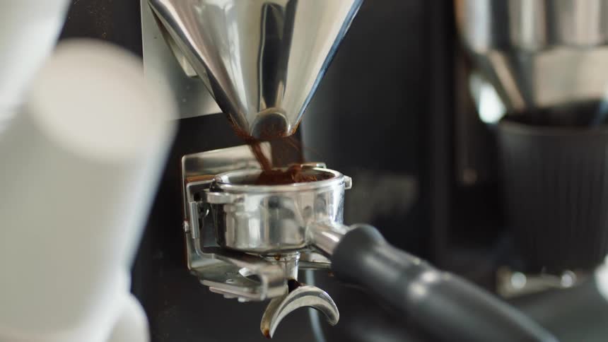 Freshly ground coffee pouring on the container for an espresso machine