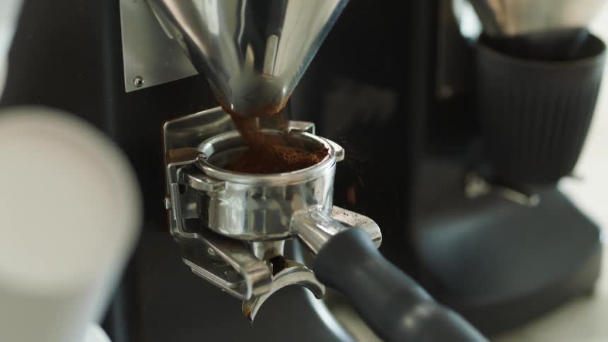 A coffee machine pouring coffee grounds into a scoop